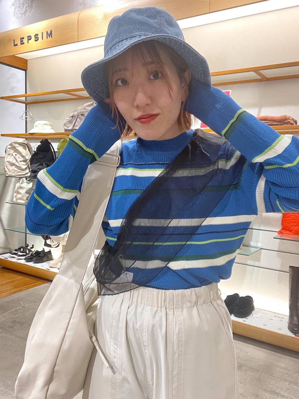 ホワイト系のショルダーバッグ、ホワイト系のカーゴパンツ、ブルー系のニット/セーターを着用したレディースの春コーディネートの4枚目の写真