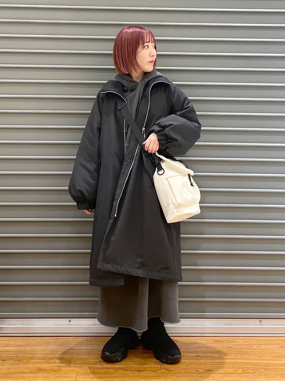 ブラック系のその他アウター、ブラック系のブーツ、ホワイト系のショルダーバッグを着用したレディースの冬コーディネートの3枚目の写真