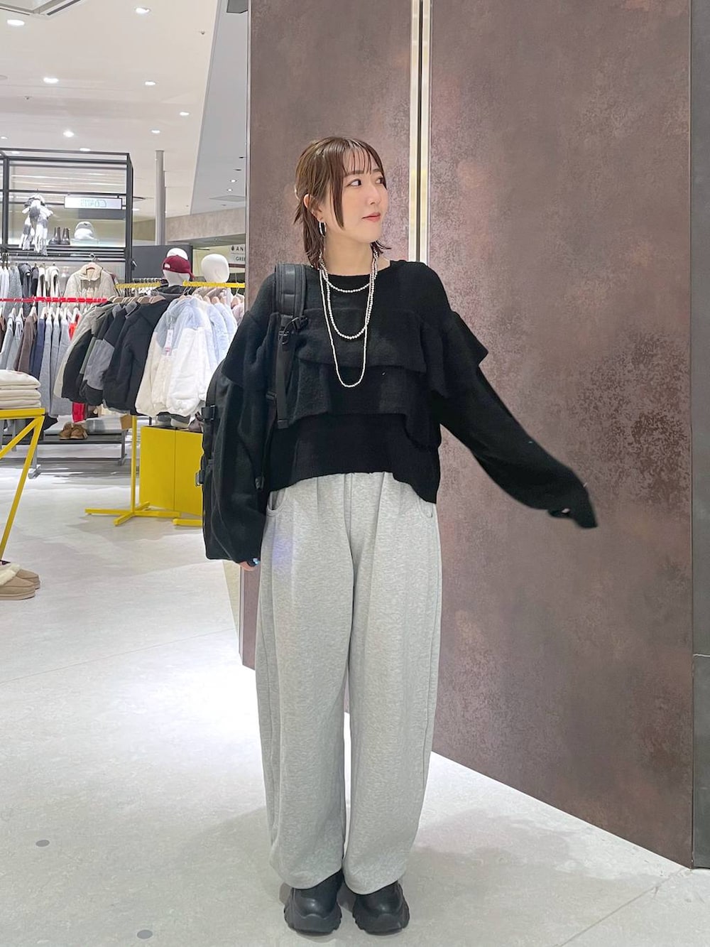 ブラック系のバックパック/リュック、グレー系のスウェットパンツ、ブラック系のニット/セーターを着用したレディースの冬コーディネートの2枚目の写真