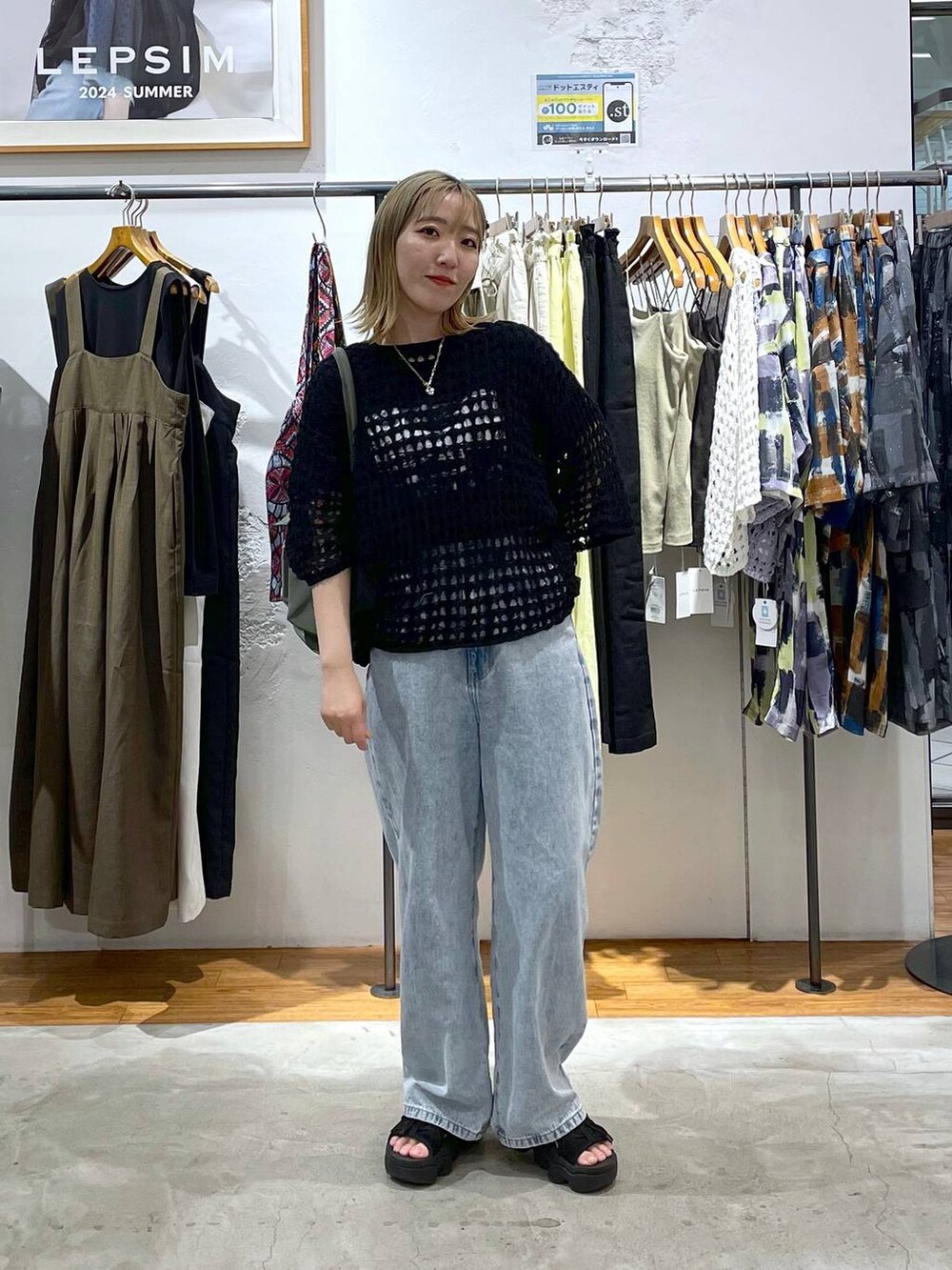 グリーン系のショルダーバッグ、ブルー系のデニムパンツ、ブラック系のニット/セーターを着用したレディースの春コーディネートの2枚目の写真