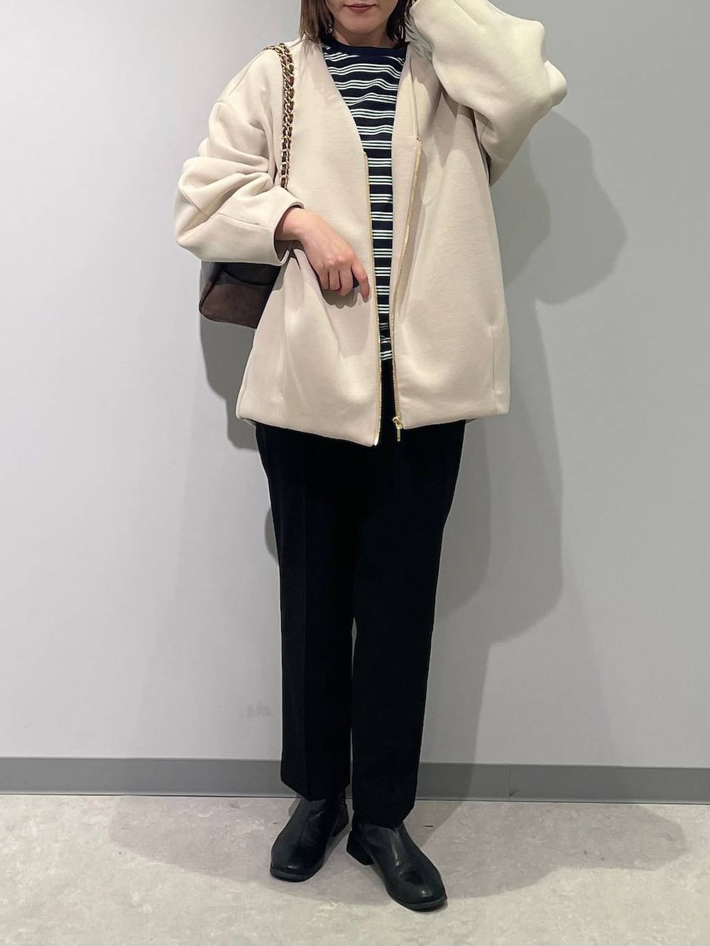 ホワイト系のブルゾン、ブラウン系のショルダーバッグ、ブラック系のスラックスを着用したレディースの春コーディネートの5枚目の写真