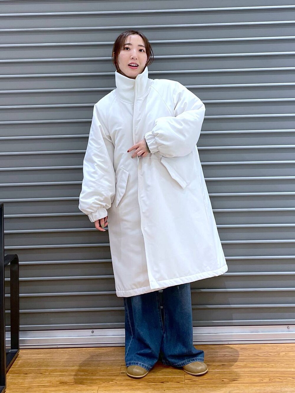 ブルー系のデニムパンツ、ブラウン系のブーツ、ベージュ系のニット/セーターを着用したレディースの秋コーディネートの2枚目の写真