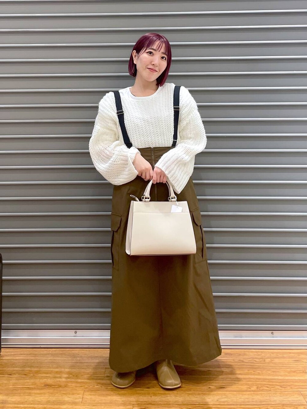 ブラウン系のブーツ、ホワイト系のニット/セーター、ブラウン系のスカートを着用したレディースの冬コーディネートの2枚目の写真