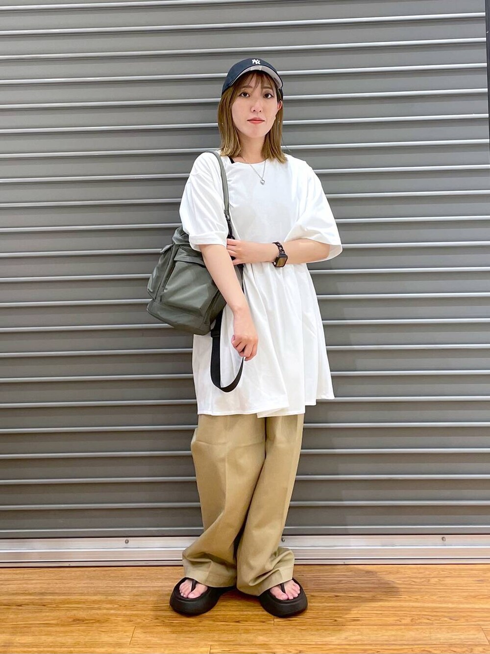 ブラック系のサンダル、グリーン系のショルダーバッグ、ホワイト系のTシャツ/カットソーを着用したレディースの夏コーディネートの3枚目の写真