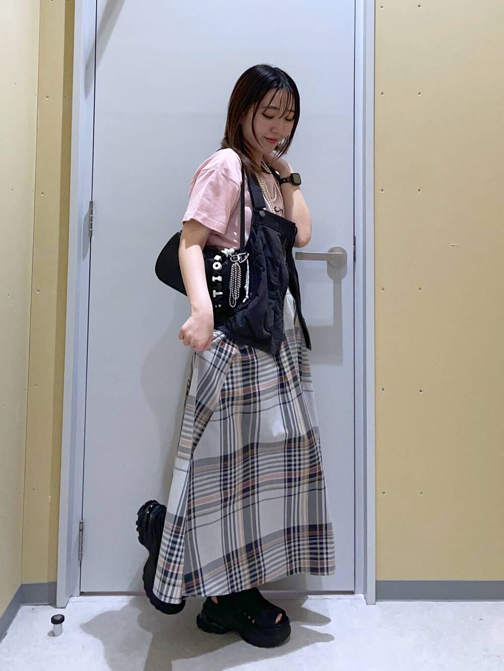 グレー系のベスト、ブラック系のトートバッグ、ベージュ系のスカートを着用したレディースの春コーディネートの3枚目の写真