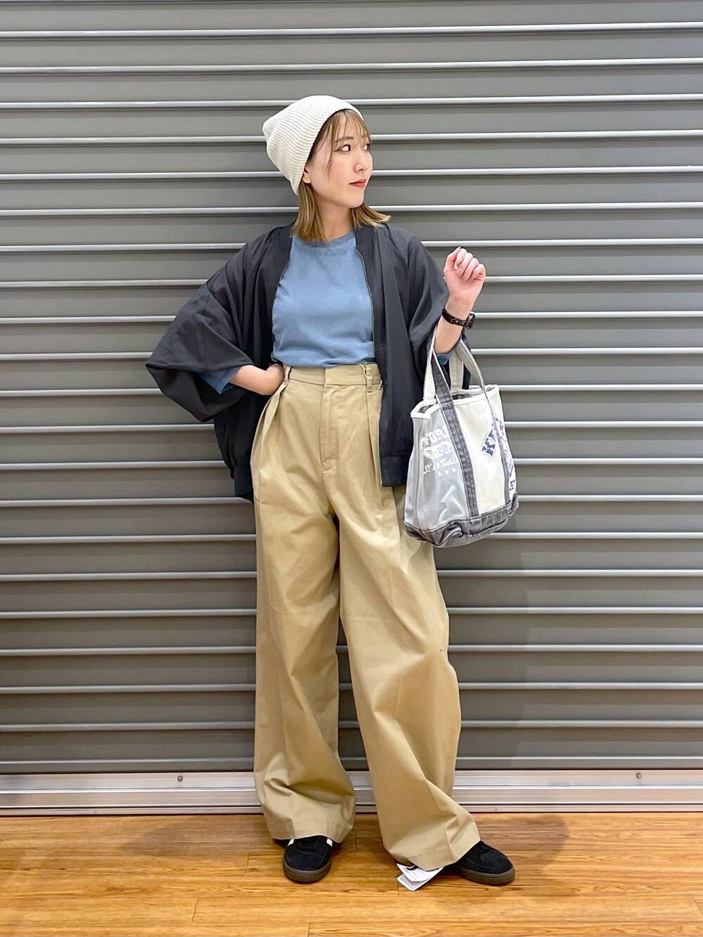 ベージュ系のチノパンツ、グレー系のブルゾン、ブラック系のスニーカーを着用したレディースの夏コーディネートの2枚目の写真