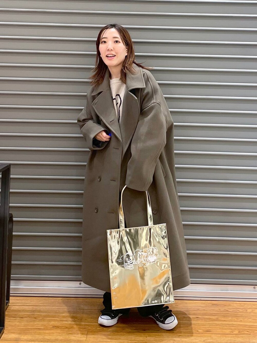 グリーン系のチェスターコート、ブラック系のその他パンツ、ゴールド系のトートバッグを着用したレディースの冬コーディネートの3枚目の写真