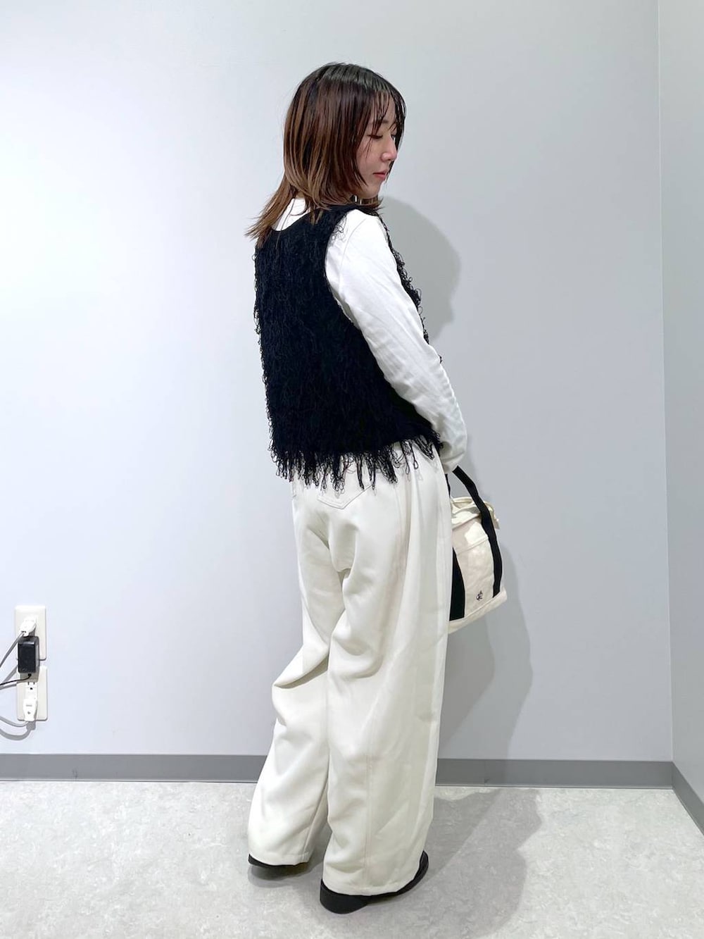 ホワイト系のトートバッグ、ホワイト系のその他パンツ、ブラック系のベストを着用したレディースの春コーディネートの3枚目の写真