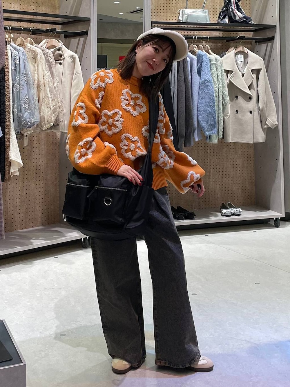 ブラック系のショルダーバッグ、ブラック系のデニムパンツ、オレンジ系のニット/セーターを着用したレディースの冬コーディネートの4枚目の写真