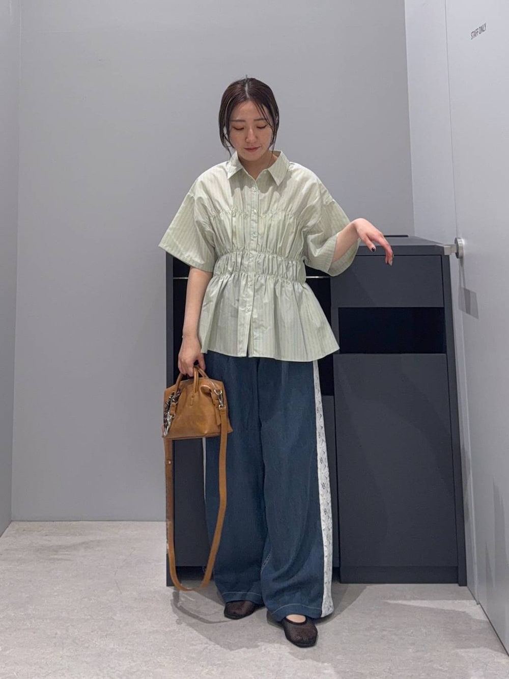 ブラウン系のボストンバッグ、グリーン系のTシャツ/カットソー、ブルー系のデニムパンツを着用したレディースの夏コーディネートの2枚目の写真