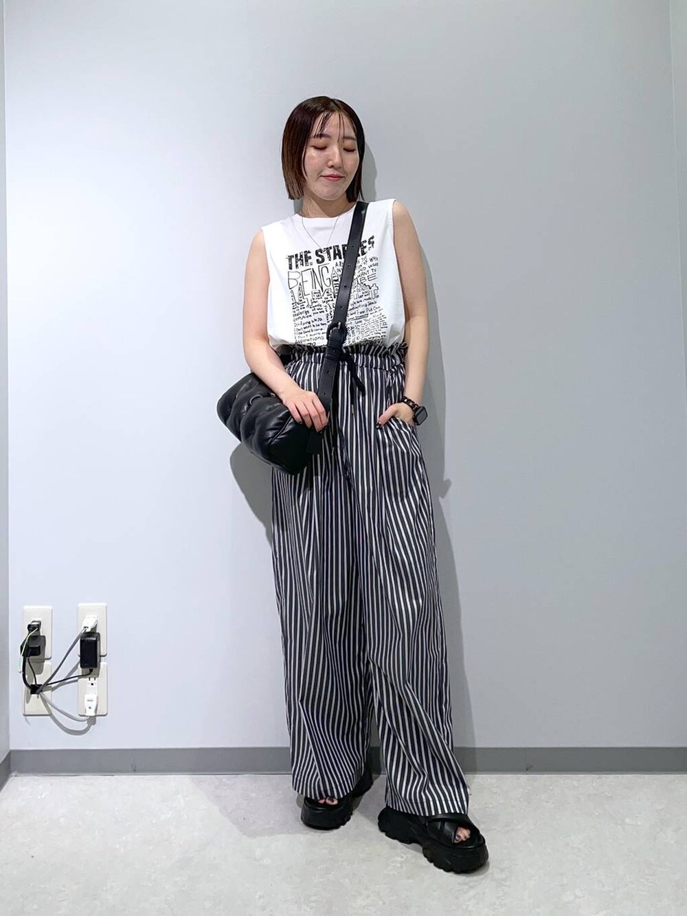 ブラック系のサンダル、ブラック系のショルダーバッグ、ホワイト系のTシャツ/カットソーを着用したレディースの夏コーディネートの3枚目の写真