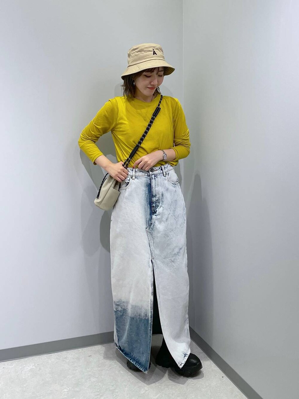 グレー系のショルダーバッグ、ブルー系のデニムスカート、イエロー系のTシャツ/カットソーを着用したレディースの秋コーディネートの2枚目の写真