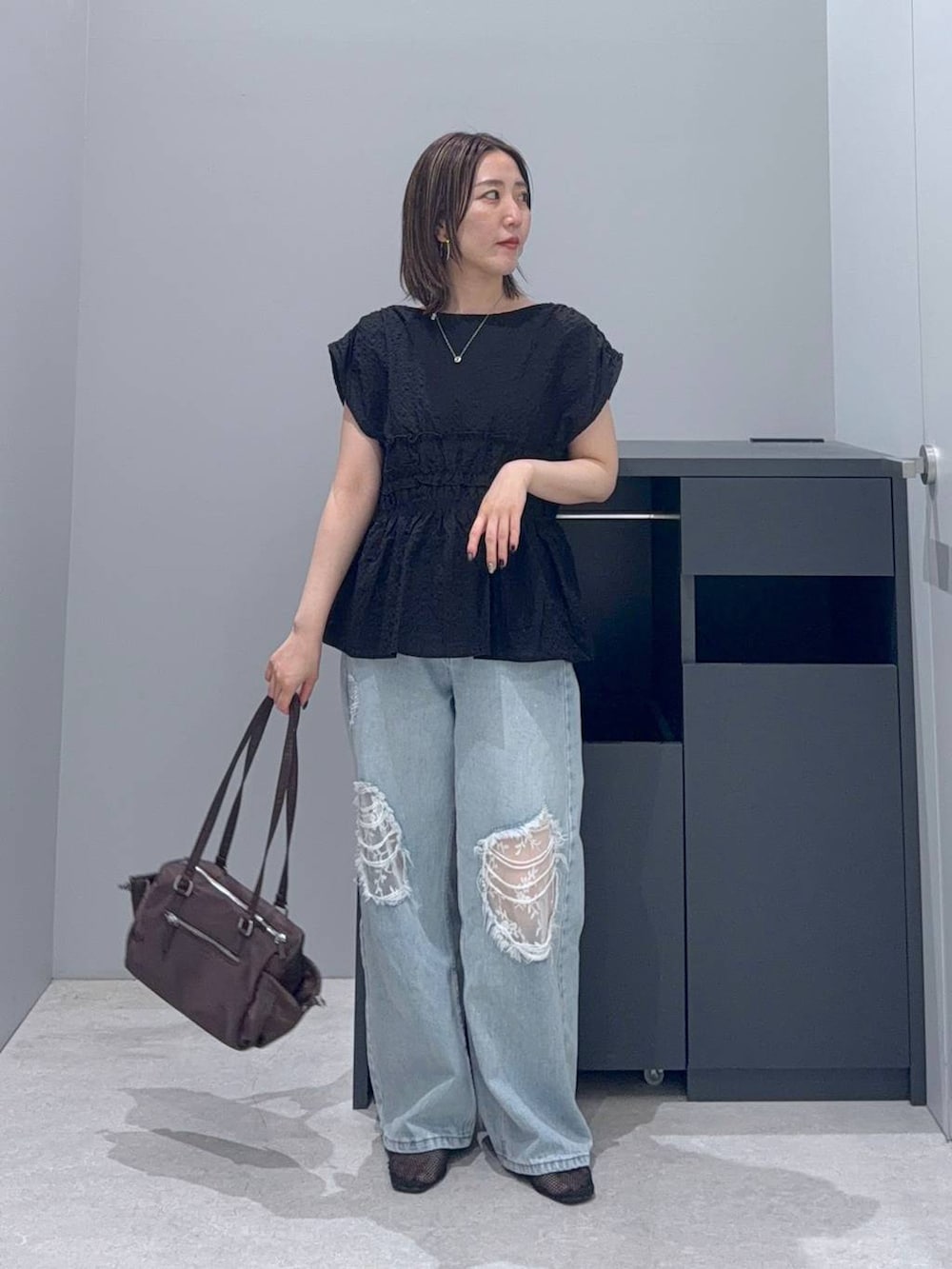 ブルー系のデニムパンツ、ブラック系のシャツ/ブラウス、ブラウン系のボストンバッグを着用したレディースの夏コーディネートの2枚目の写真