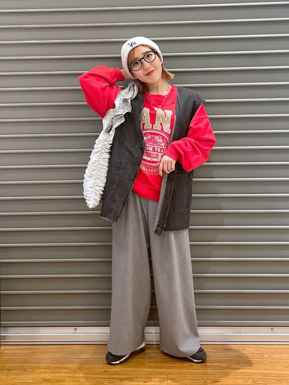 レッド系のスウェット、シルバー系のトートバッグ、グレー系のスラックスを着用したレディースの春コーディネートの2枚目の写真