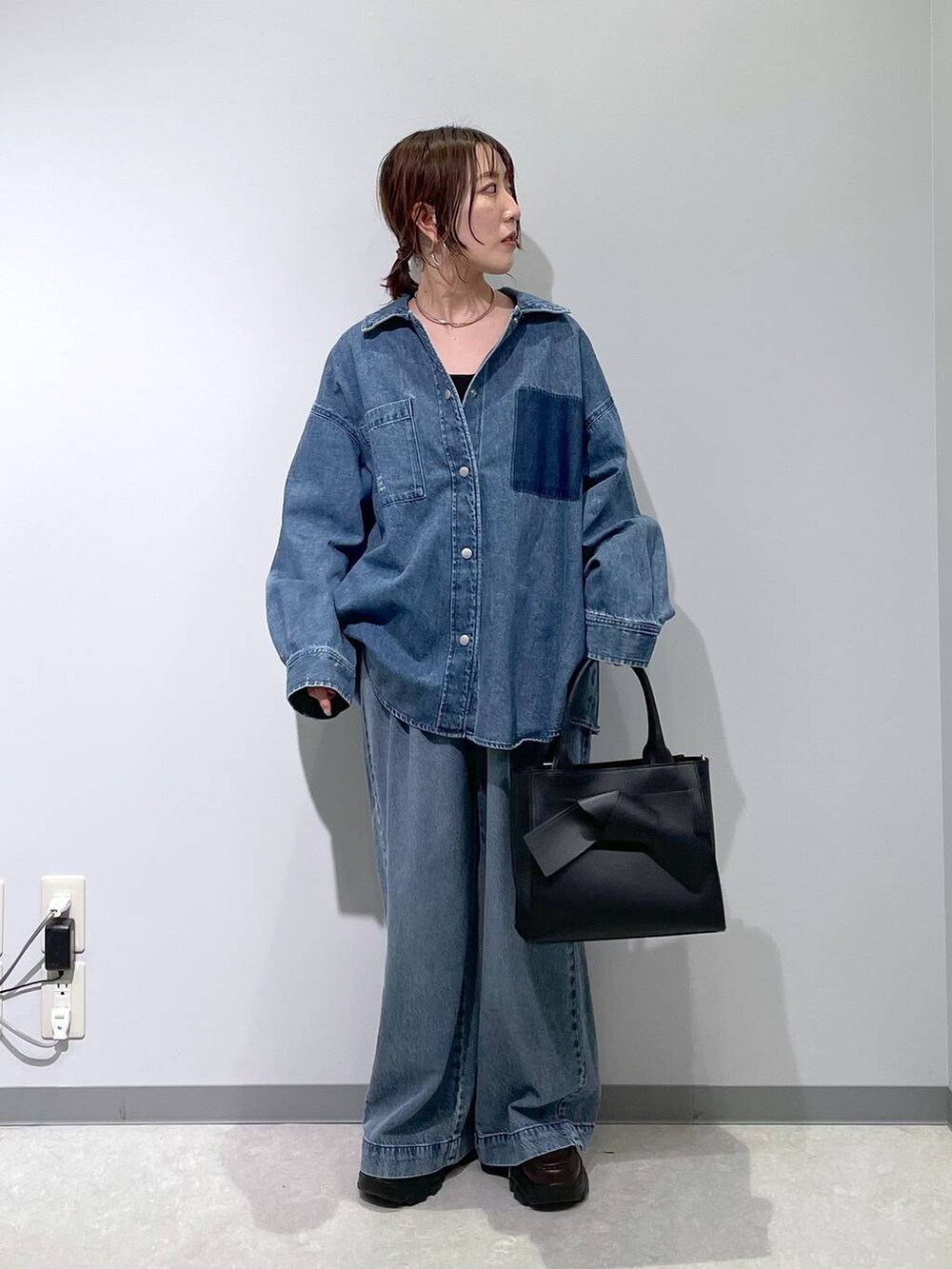 ブルー系のデニムパンツ、ブラック系のハンドバッグ、ブラウン系のローファーを着用したレディースの冬コーディネートの4枚目の写真