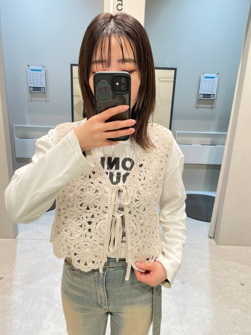 ブルー系のデニムパンツ、ベージュ系のベストを着用したレディースの春コーディネートの2枚目の写真