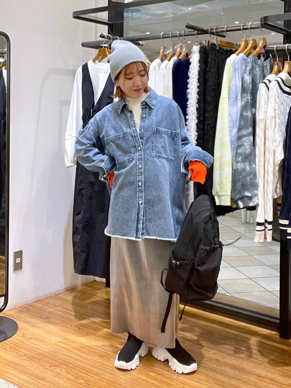 グレー系のスカート、ブラック系のバックパック/リュック、ブルー系のシャツ/ブラウスを着用したレディースの冬コーディネートの3枚目の写真