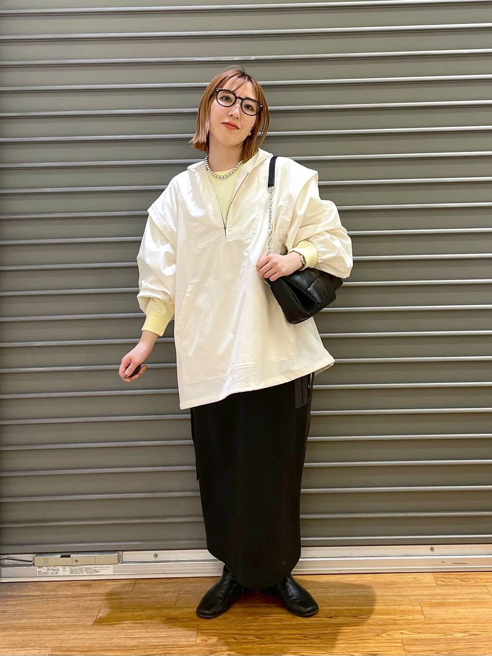 ブラック系のショルダーバッグ、ホワイト系のその他アウター、イエロー系のTシャツ/カットソーを着用したレディースの春コーディネートの3枚目の写真