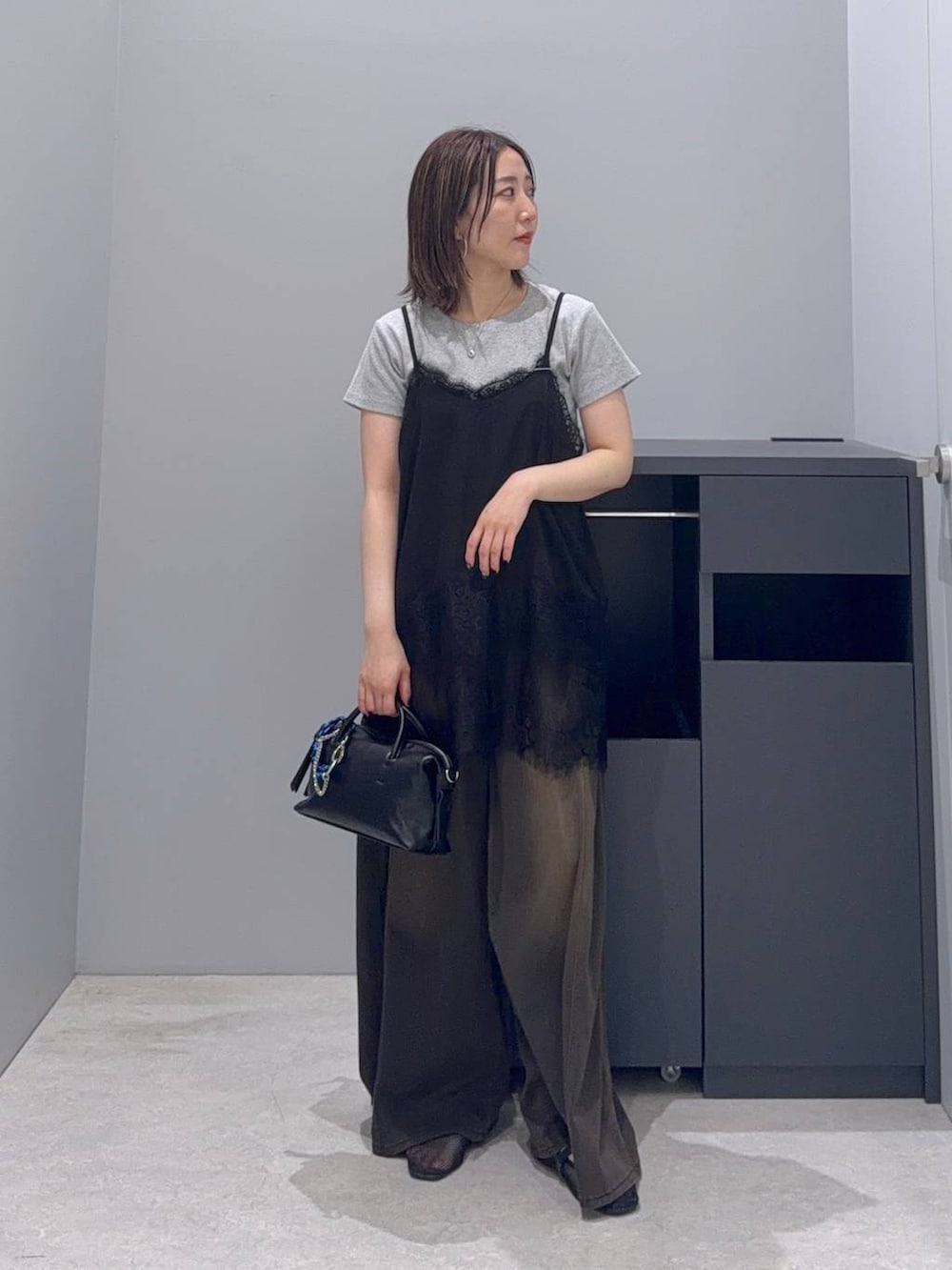 ブラウン系のデニムパンツ、ブラック系のボストンバッグ、ブラック系のTシャツ/カットソーを着用したレディースの夏コーディネートの2枚目の写真