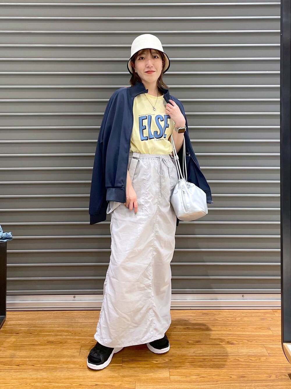 ブラック系のサンダル、シルバー系のショルダーバッグ、グレー系のスカートを着用したレディースの春コーディネートの2枚目の写真