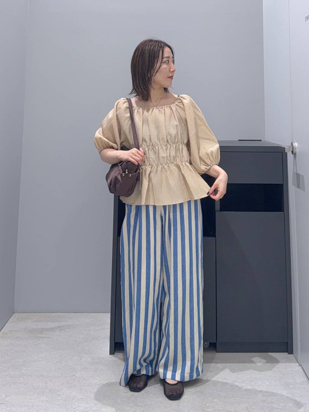 ベージュ系のシャツ/ブラウス、ブルー系のその他パンツ、ブラウン系のボストンバッグを着用したレディースの夏コーディネートの2枚目の写真