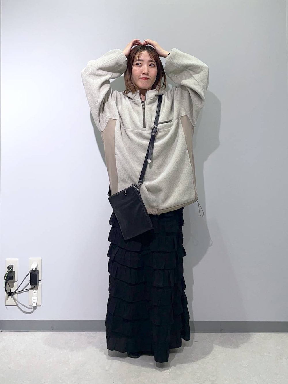 ブラック系のスカート、ブラック系のショルダーバッグ、ベージュ系のパーカーを着用したレディースの秋コーディネートの4枚目の写真