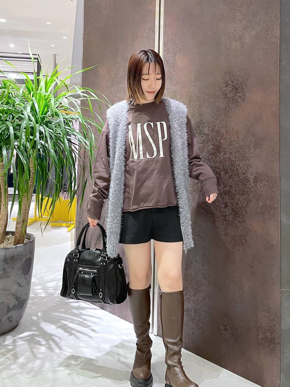 ブラック系のボストンバッグ、グレー系のベスト、ブラウン系のスウェットを着用したレディースの秋コーディネートの3枚目の写真