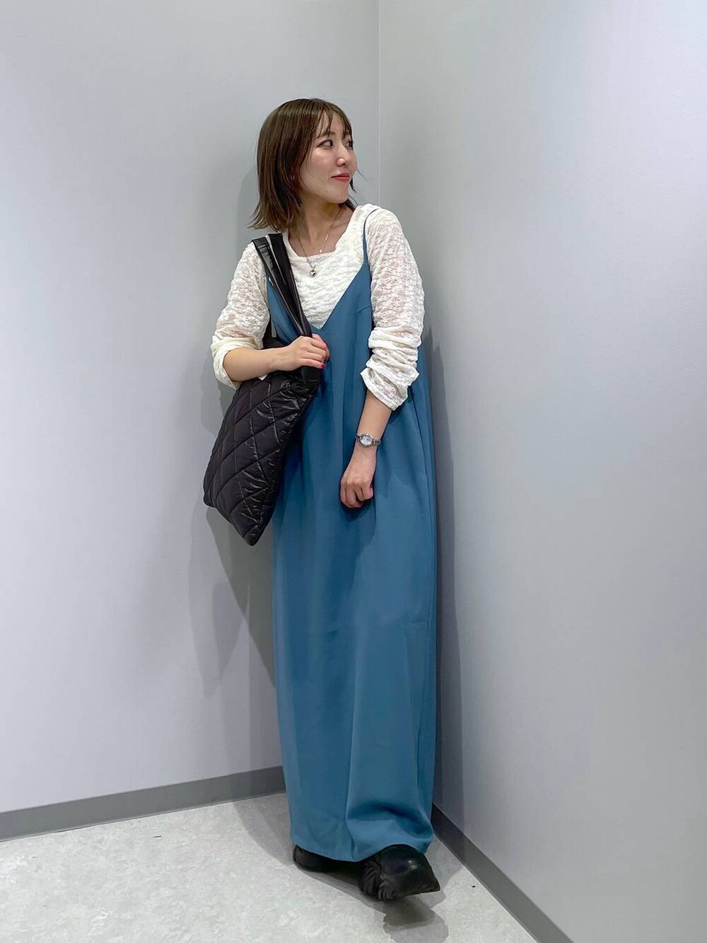 ブラック系のトートバッグ、ブルー系のワンピース、ホワイト系のTシャツ/カットソーを着用したレディースの秋コーディネートの2枚目の写真