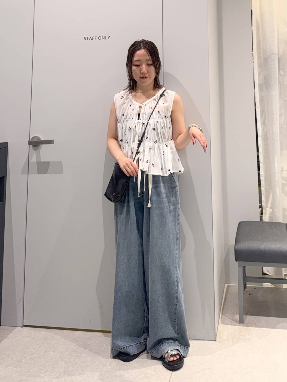 シルバー系のサンダル、ブラック系のショルダーバッグ、ブルー系のデニムパンツを着用したレディースの夏コーディネートの2枚目の写真