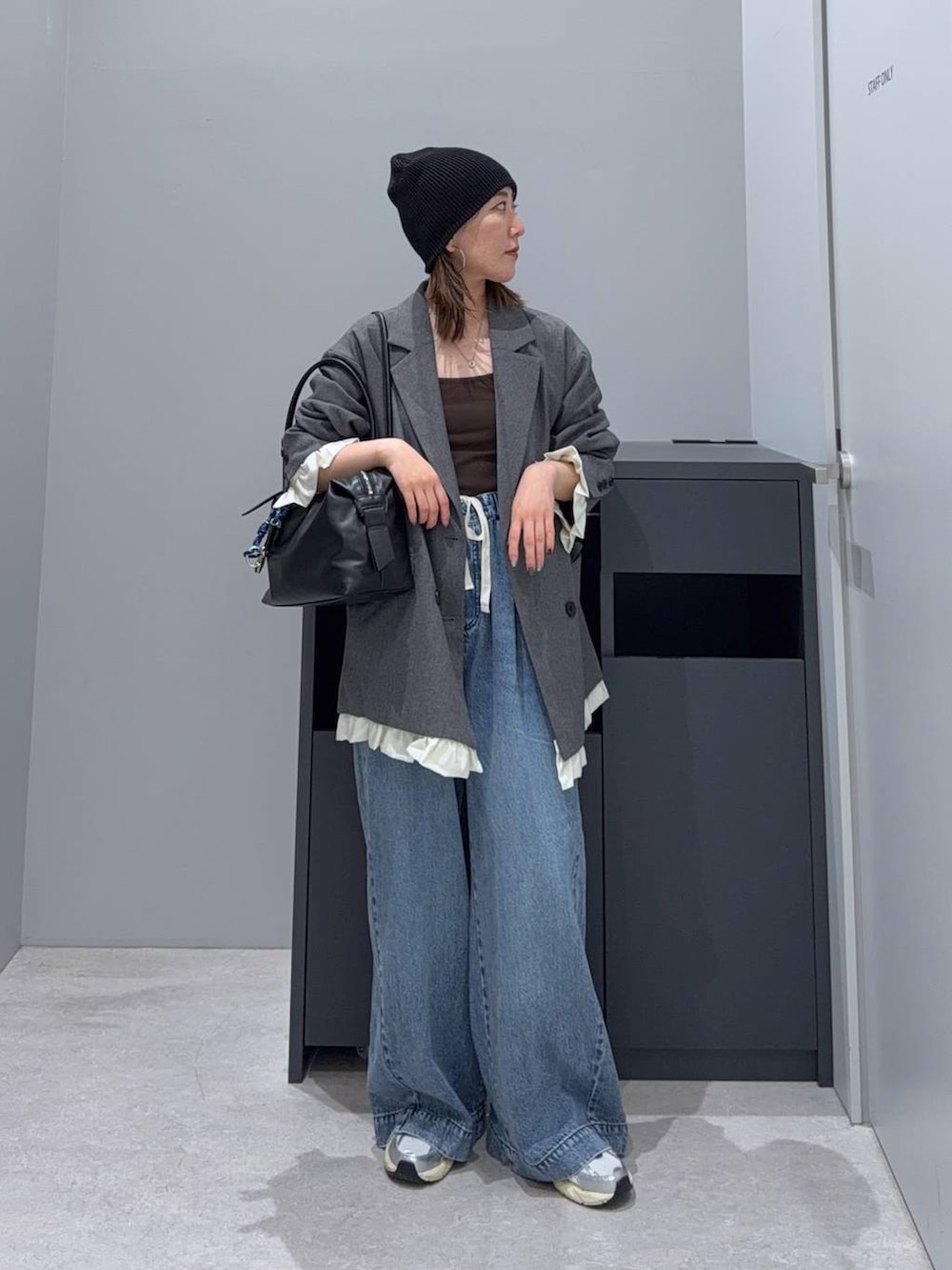 ブラック系のボストンバッグ、ブルー系のデニムパンツ、グレー系のテーラードジャケットを着用したレディースの秋コーディネートの2枚目の写真