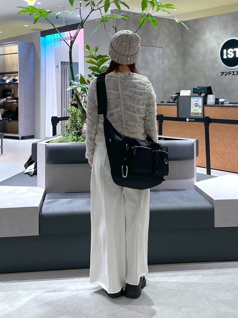 ブラック系のショルダーバッグ、ブラック系のブーツ、ホワイト系のスウェットパンツを着用したレディースの冬コーディネートの3枚目の写真