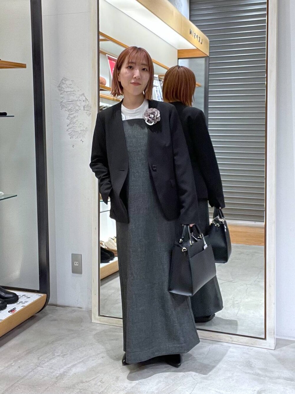 ブラック系のノーカラージャケット、ホワイト系のシャツ/ブラウス、ブラック系のショルダーバッグを着用したレディースの冬コーディネートの2枚目の写真