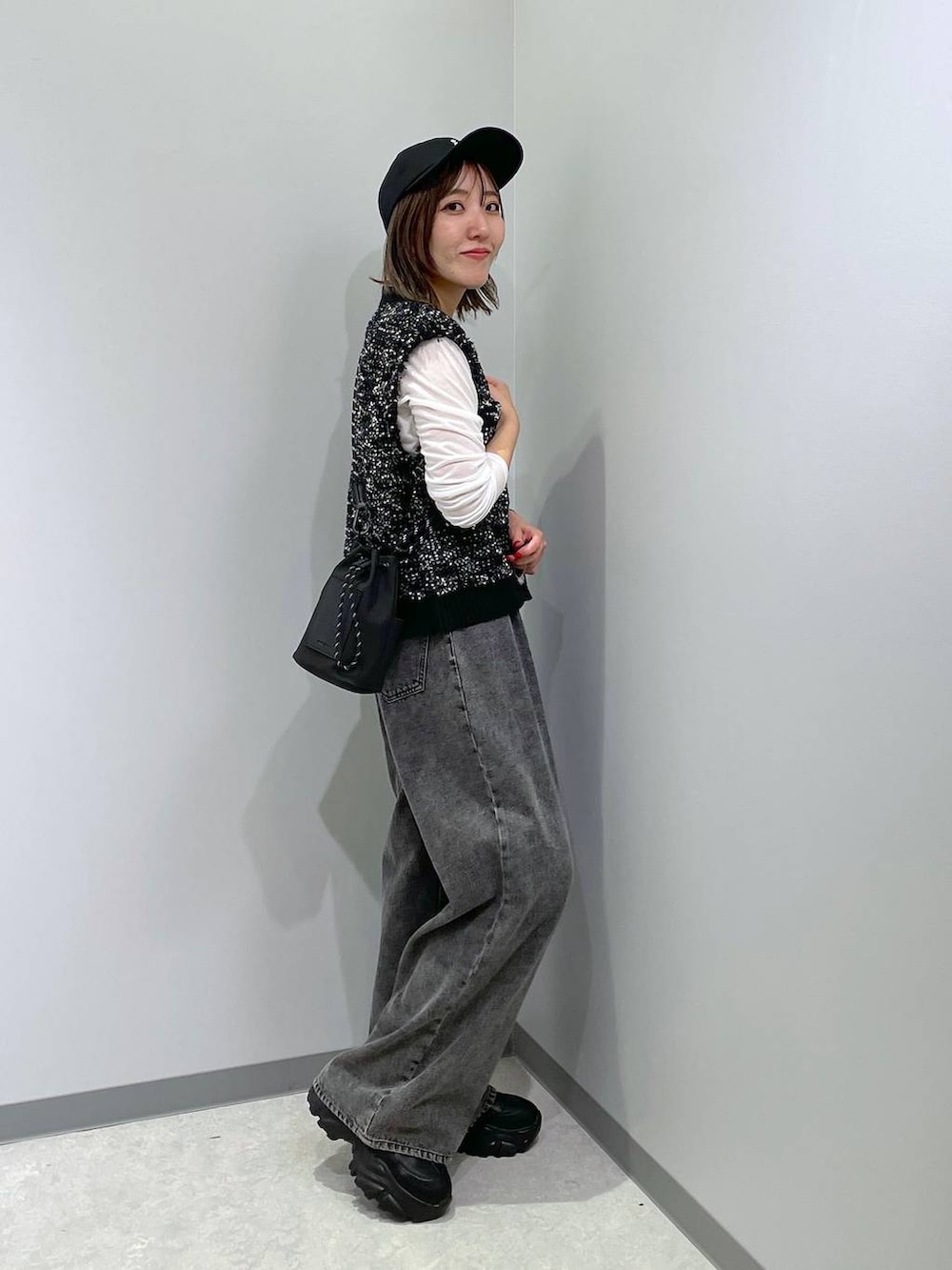 ブラック系のベスト、ホワイト系のTシャツ/カットソー、グレー系のデニムパンツを着用したレディースの秋コーディネートの3枚目の写真