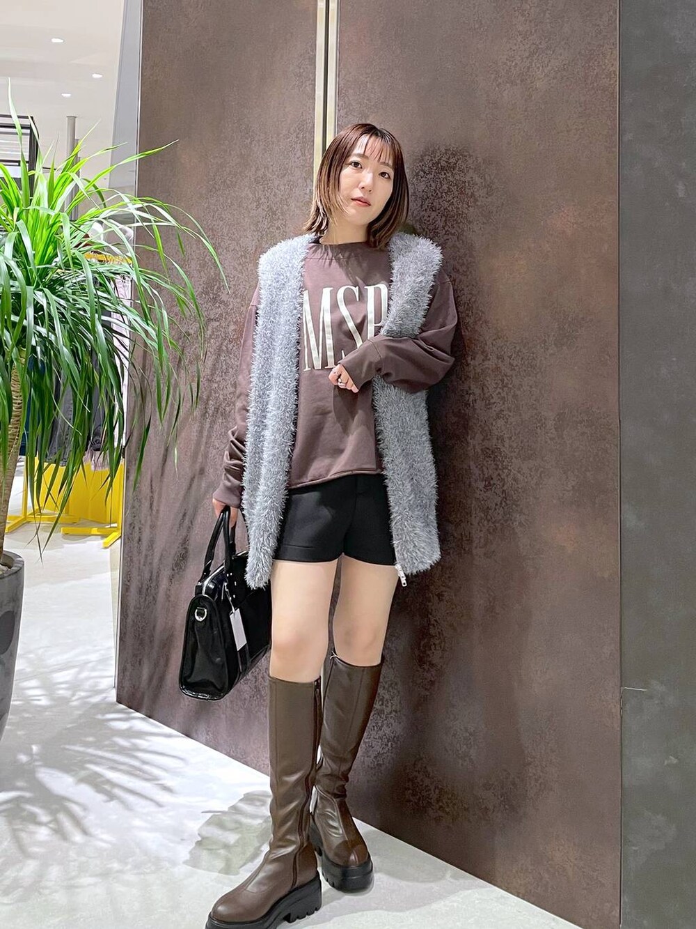 ブラック系のボストンバッグ、グレー系のベスト、ブラウン系のスウェットを着用したレディースの秋コーディネートの2枚目の写真