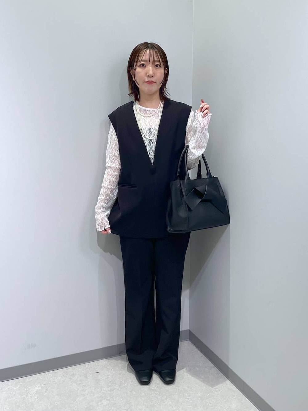 ブラック系のローファー、ブラック系のハンドバッグ、ブラック系のスーツセットを着用したレディースの冬コーディネートの3枚目の写真