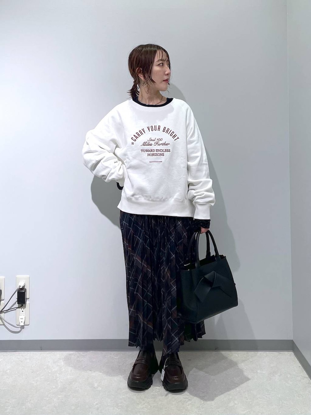 ブルー系のスカート、ブラック系のハンドバッグ、ブラック系のTシャツ/カットソーを着用したレディースの冬コーディネートの4枚目の写真