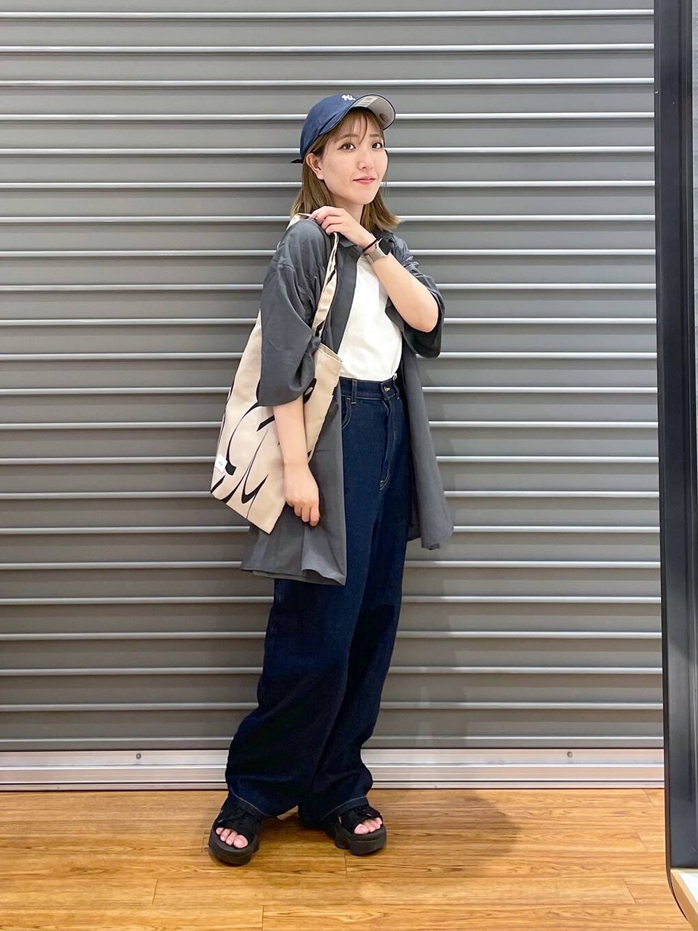 グレー系のシャツ/ブラウス、ブラウン系のトートバッグ、ブルー系のデニムパンツを着用したレディースの夏コーディネートの3枚目の写真