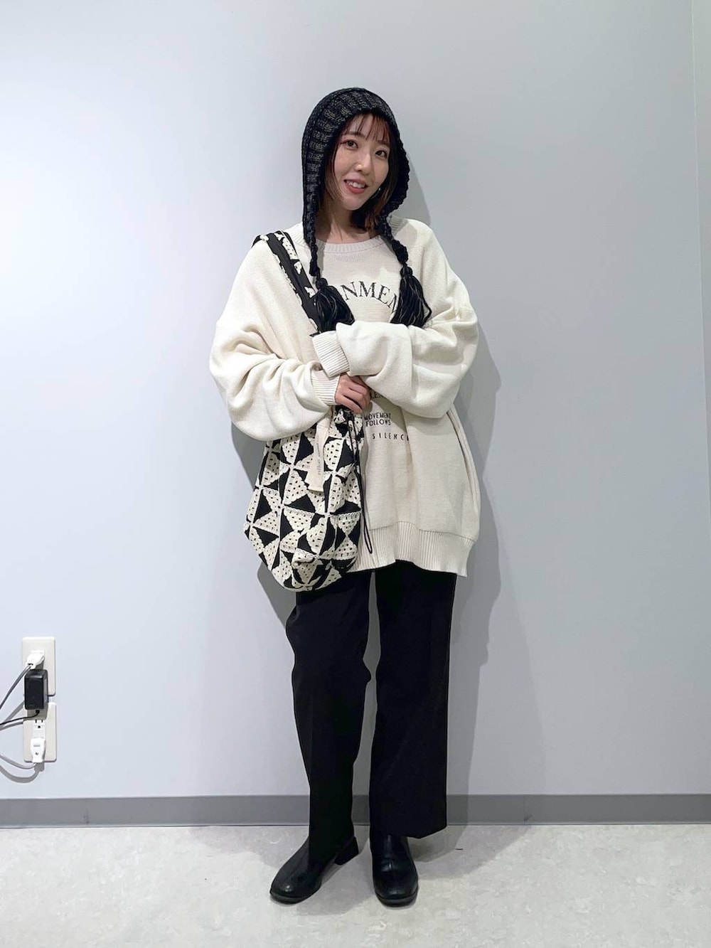 ブラック系のスラックス、その他のトートバッグ、ホワイト系のニット/セーターを着用したレディースの秋コーディネートの3枚目の写真