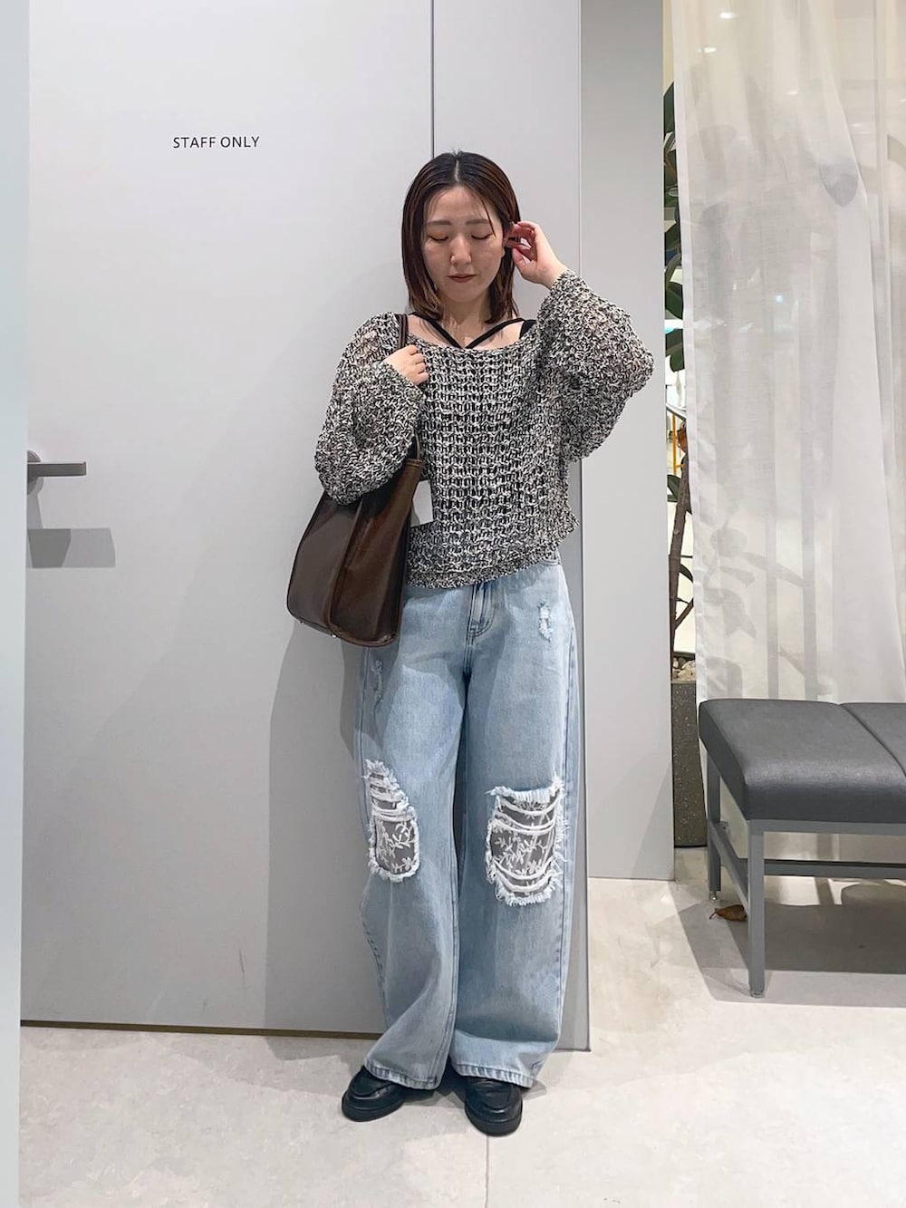 ブルー系のデニムパンツ、ブラウン系のトートバッグ、ブラック系のニット/セーターを着用したレディースの春コーディネートの3枚目の写真