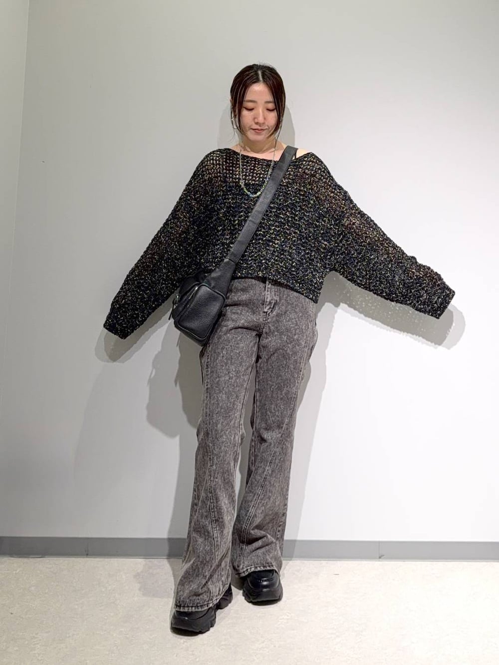 ブラック系のニット/セーター、ブラック系のデニムパンツ、ブラック系のショルダーバッグを着用したレディースの夏コーディネートの2枚目の写真