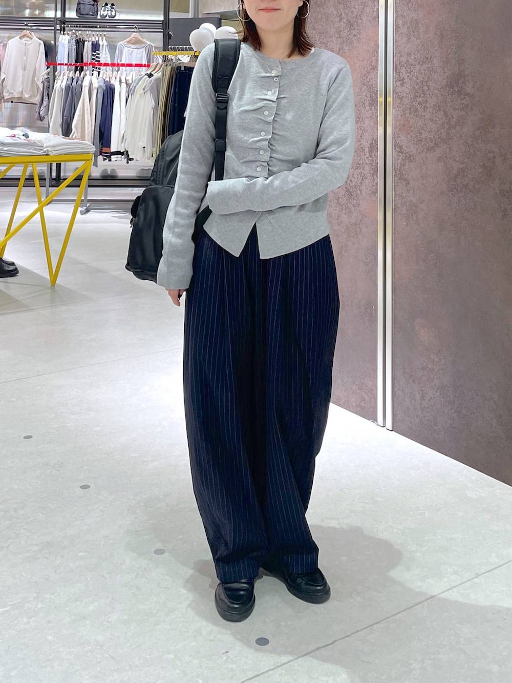 ブルー系のその他パンツ、ブラック系のバックパック/リュック、グレー系のカーディガン/ボレロを着用したレディースの春コーディネートの3枚目の写真