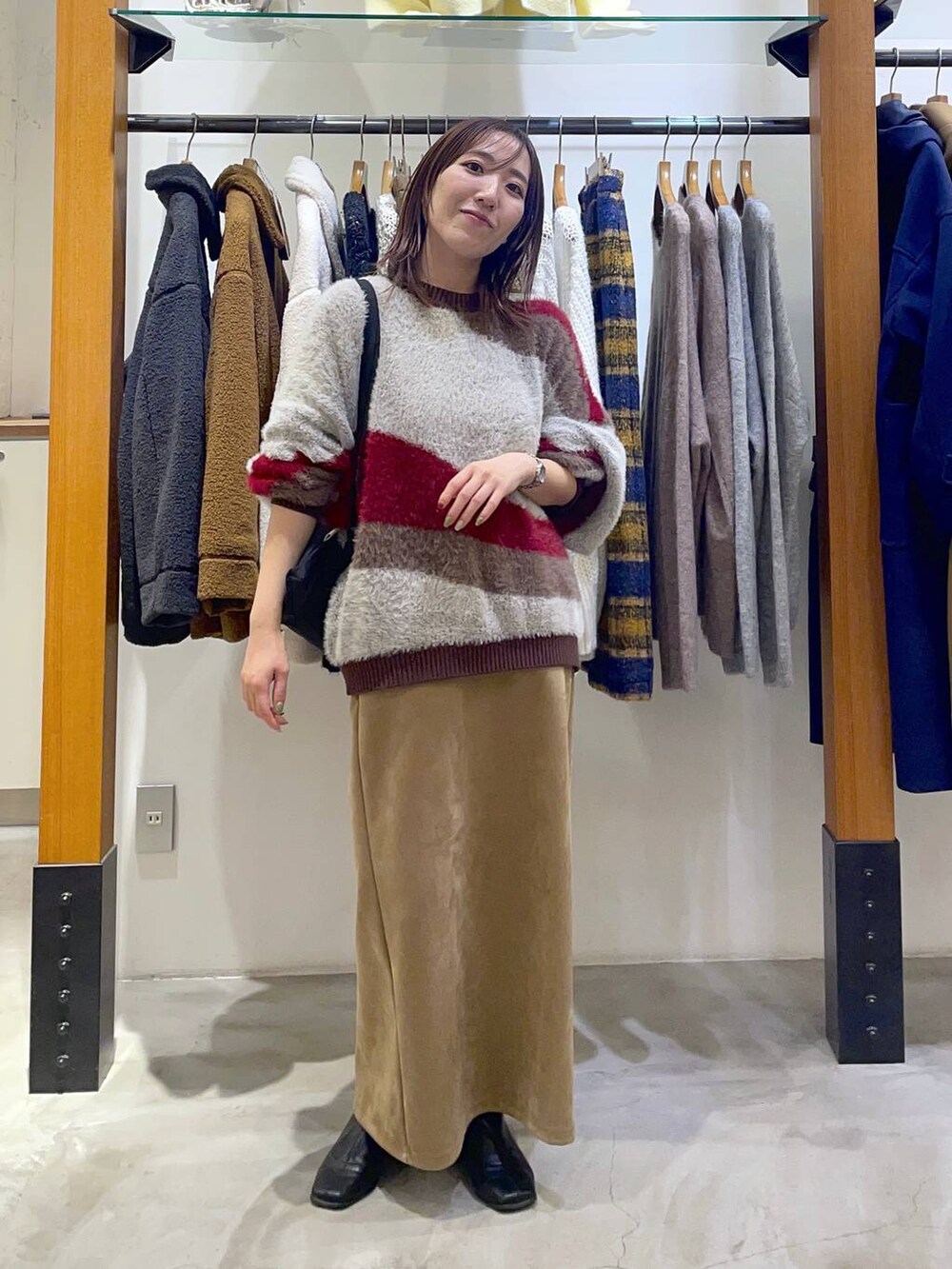 ブラック系のショルダーバッグ、ベージュ系のスカート、ブラウン系のニット/セーターを着用したレディースの冬コーディネートの3枚目の写真
