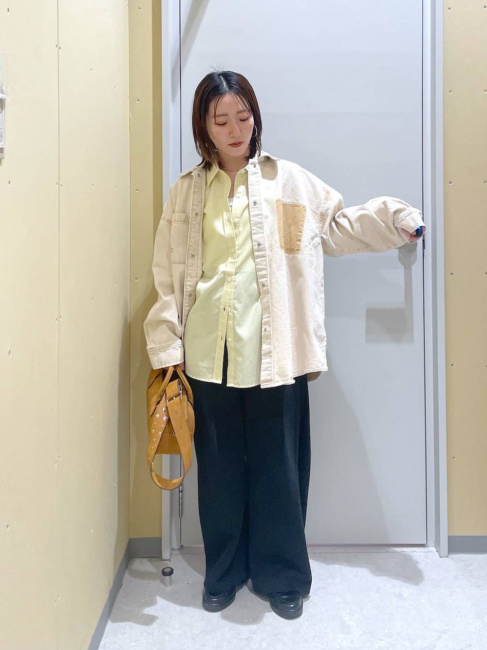 イエロー系のシャツ/ブラウス、ブラウン系のボストンバッグを着用したレディースの春コーディネートの2枚目の写真