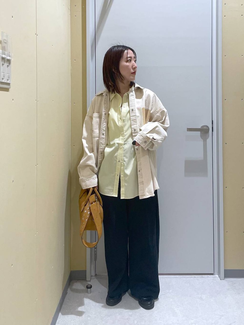 イエロー系のシャツ/ブラウス、ブラウン系のボストンバッグを着用したレディースの春コーディネートの3枚目の写真