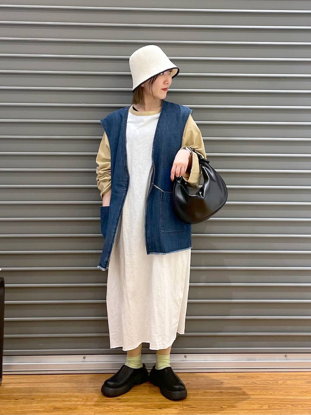 ベージュ系のワンピース、ブラック系のショルダーバッグ、ブルー系のベストを着用したレディースの春コーディネートの2枚目の写真