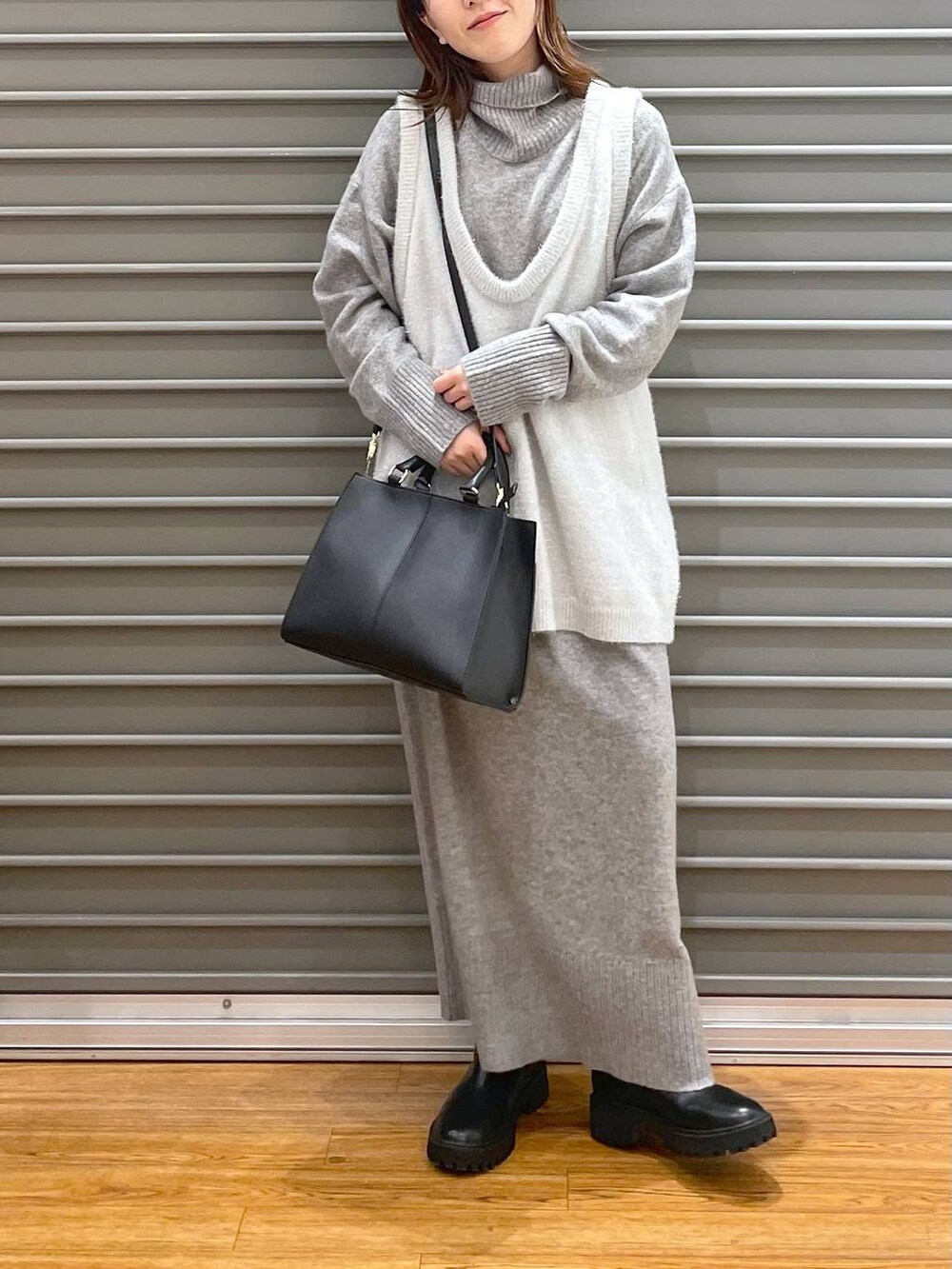 ブラック系のブーツ、グレー系のワンピース、ブラック系のショルダーバッグを着用したレディースの冬コーディネートの3枚目の写真