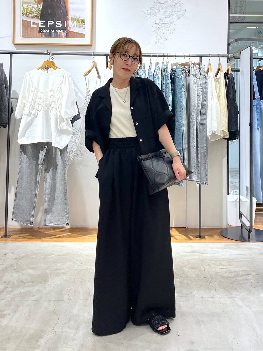 ブラック系のその他パンツ、ブラック系のシャツ/ブラウス、ブラック系のクラッチバッグを着用したレディースの夏コーディネートの2枚目の写真