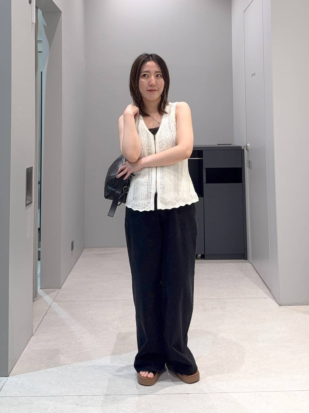ブラック系のサンダル、ブラック系のショルダーバッグ、ブラック系のデニムパンツを着用したレディースの夏コーディネートの3枚目の写真
