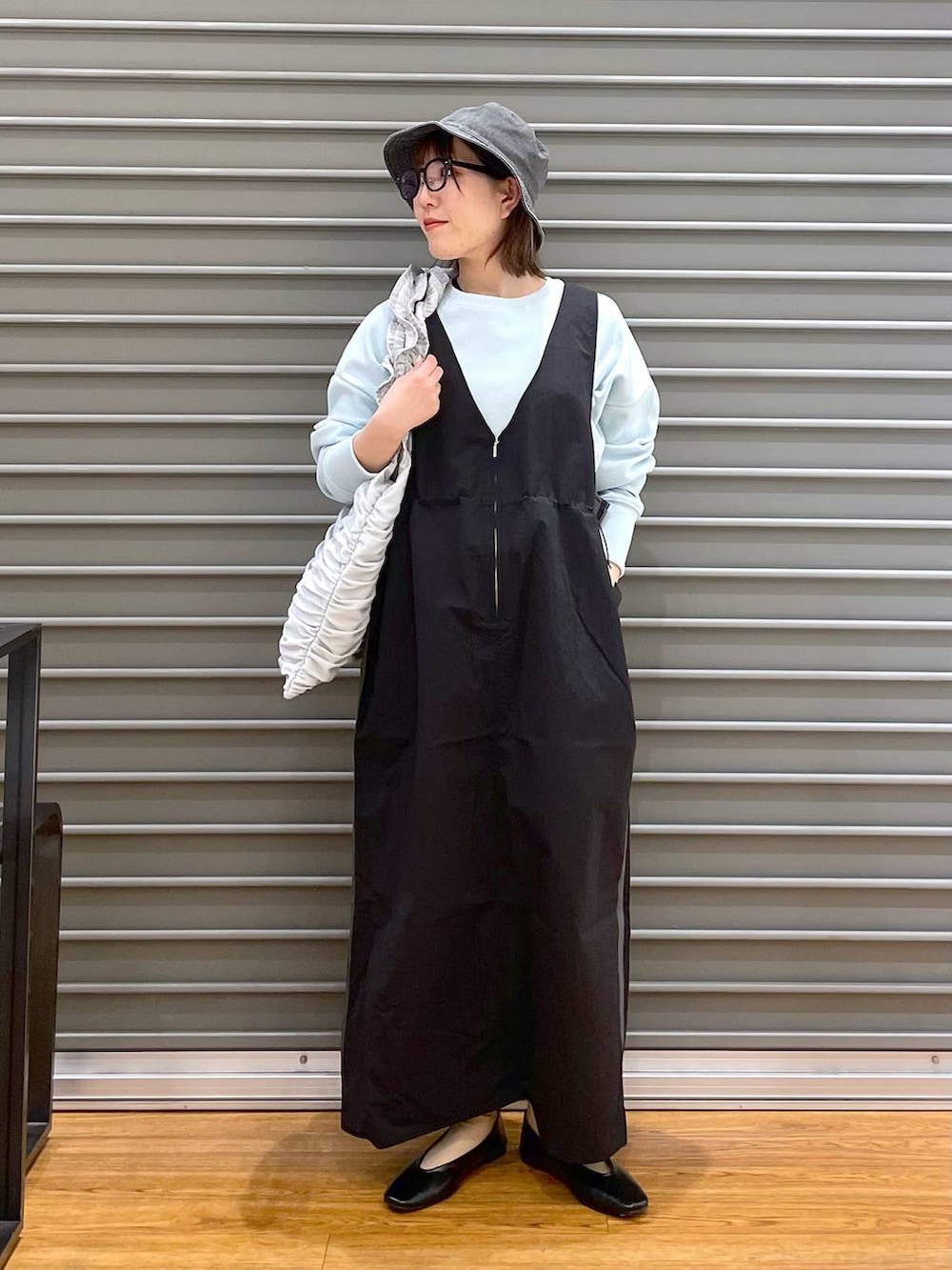 シルバー系のトートバッグ、ブラック系のパンプス、ブラック系のジャンパースカートを着用したレディースの春コーディネートの2枚目の写真