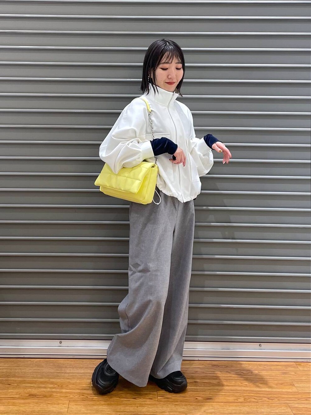 ブルー系のTシャツ/カットソー、イエロー系のショルダーバッグ、グレー系のスラックスを着用したレディースの春コーディネートの2枚目の写真